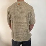 Camisa tejida de manga corta color verde oliva, con cuello tipo polo y cierre frontal con botones.