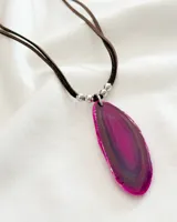 Collar con colgante de piedra ágata fucsia con vetas marrones, engarzada con detalles metálicos plateados y cordón de cuero marrón.