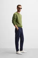 Pantalón negro de corte slim fit, confeccionado en tejido elástico. Cuenta con cintura elástica, bolsillos frontales y traseros de vivo. Cierre frontal con cremallera y botón.