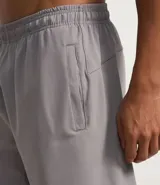 Bermuda deportiva gris de microfibra con cintura elástica ajustable con cordón y bolsillos laterales con cremallera.