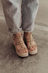 Sandalias negras de plataforma con tiras de gamuza y esferas doradas decorativas.