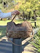 Bolso de cuero marrón con doble correa, interior forrado con bolsillos y llavero, cierre de lado a lado.