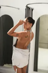 Vestido corto plateado con escote drapeado tipo cowl neck y tirantes finos. Presenta un corte ajustado y aberturas pronunciadas en los laterales.