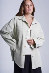 Sobrecamisa color beige de gabardina con cuello camisero, cierre frontal con botones a presión, dos bolsillos de parche en el pecho y corte holgado.