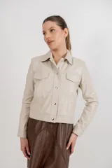 Campera corta de cuero ovino color borgoña, estilo jeanera, con cuello clásico, bolsillos con solapa y cierre frontal con broches metálicos.