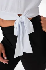Remera blanca de corte crop con escote redondo y detalle de lazo en la cintura.