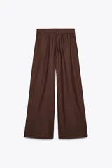 Pantalón marrón de tiro alto con cintura elástica en la espalda, bolsillos laterales, pliegues en la parte delantera y bordados combinados a tono en el ruedo.