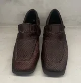 Mocasín de cuero color marrón con textura labrada y suela plana.