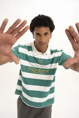 Remera estilo rugby a rayas horizontales verdes y blancas, con cuello blanco tipo polo y mangas cortas. Tiene un logo bordado en el pecho.