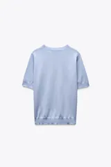 Top celeste de punto fino con cuello redondo y mangas cortas.