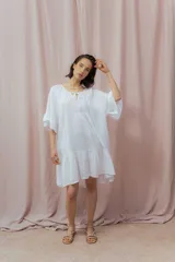 Vestido corto color beige de lino, con escote redondeado con lazo y mangas cortas amplias.