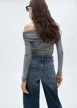 Top gris de lúrex con diseño off-shoulder, hombros descubiertos, mangas largas y detalles drapeados.