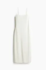 Vestido midi blanco de punto suave con escote redondo profundo y espalda escotada. Modelo entallado con breteles spaghetti que se entrelazan en bucles y se atan en la espalda.