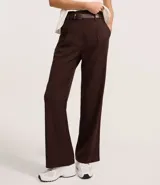 Pantalón de vestir marrón chocolate, de corte recto, con cintura alta, trabillas para cinturón, cierre con botón y cremallera, pliegues frontales y cinturón con hebilla.