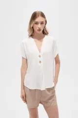 Blusa blanca de viscosa, corte holgado, con cuello en V y cierre frontal con dos botones de madera.