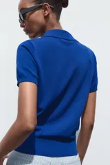 Top azul eléctrico de punto, con cuello polo, manga corta y cierre frontal con botones negros.
