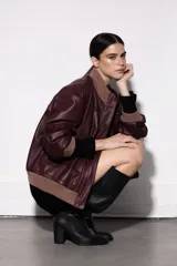 Chaqueta tipo bomber de cuero color burdeos, con cuello, puños y ruedo de punto acanalado color beige.