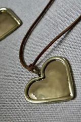 Collar con dije de corazón dorado y cordón marrón.