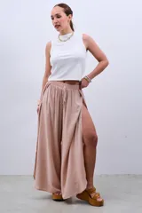 Pantalón palazzo color beige de fibrana con cintura elastizada y cordón ajustable. Presenta aberturas laterales desde la cadera.