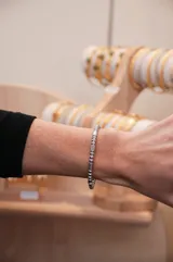 Pulsera rígida plateada con cuentas cilíndricas y esféricas.