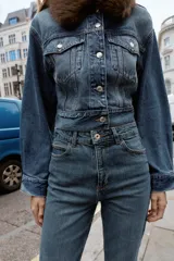 Pantalón de jean azul de tiro alto, corte mom fit, tobillero y con cinco bolsillos. Cierre frontal con cremallera y botón.