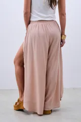 Pantalón palazzo color beige de fibrana con cintura elastizada y cordón ajustable. Presenta aberturas laterales desde la cadera.