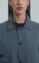 Campera gris con cuello camisero, cierre con botones a presión, múltiples bolsillos frontales con solapa y puños elásticos.