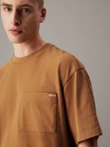 Remera color caramelo de corte holgado, confeccionada en 100% algodón. Tiene mangas cortas, cuello redondo y un bolsillo de parche en el pecho con etiqueta de la marca.