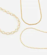 Collar de capas dorado con tres cadenas diversas: una singapura, una de eslabones delicados y una con esferas achatadas.