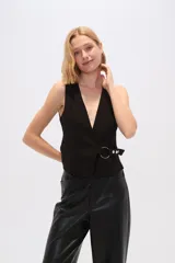 Chaleco negro sin mangas con escote en V y cierre cruzado con hebilla metálica.