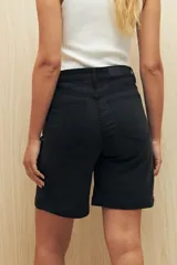 Bermuda de denim azul oscuro, de tiro alto y largo a la rodilla. Presenta bolsillos funcionales y costuras marcadas.