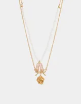 Collar corto multicadena dorada, con una cadena de eslabones y otra de perlas. Incluye dijes de zapatos de ballet rosados, moño y flor de metal dorados.