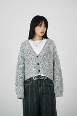 Cárdigan de punto bouclé gris con textura, escote profundo en V y cierre con botones. Con puños y dobladillo de canalé, ofrece un corte relajado y cómodo.