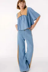 Pantalón ancho de jean celeste con paneles laterales en tela color camel con estampado sutil.