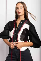 Chaleco con estampado de vaca en tonos marrones y blancos, con detalles de pasamanería en cuero.