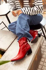 Bota texana corta de cuero color rojo, con punta fina, caña baja y taco cuadrado.
