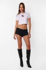 Remera corta blanca tipo baby tee, de cuello redondo y mangas cortas, confeccionada en jersey de algodón. Detalle de costuras rojas en toda la prenda y estampa de flecha con rosa en el delantero.