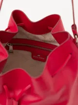 Cartera tipo bucket color rojo, de cuero, con cierre de cordón ajustable y correa larga para colgar del hombro.
