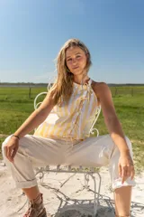 Camisa con cuello halter a rayas amarillas y blancas, con lazos en el frente.