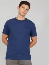 Remera azul de manga corta con cuello redondo y logo de Calvin Klein bordado en el pecho. Presenta una cinta distintiva en los hombros.