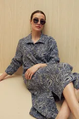 Vestido camisero midi color marrón con estampado de flores rosas, cinturón marrón y mangas largas.