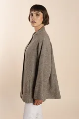 Capa marrón con bolsillos, mangas amplias y pinzas en la delantera. Terminaciones interiores envivadas. Confeccionada en lana fina sin teñir, diseñada exclusivamente por Don Baez.