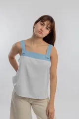 Top de tiras ancho color gris claro con detalle de canesú y tiras en color celeste.