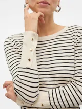 Sweater de punto con cuello redondo y mangas largas con detalle de botones en los puños. Diseño a rayas horizontales en color crudo y negro.