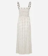 Vestido midi de algodón, color crema, con breteles finos. El corpiño presenta un diseño de crochet con motivos florales en azul marino, y la falda evasé tiene un estampado de pequeños íconos abstractos en azul.