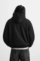 Sudadera con capucha gris confeccionada en tejido de algodón con interior rizo. Tiene manga larga, bolsillo frontal tipo canguro y acabados en rib.