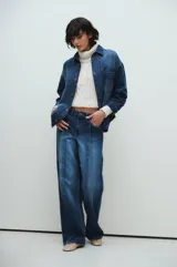 Pantalón de jean azul de corte recto y amplio, con tablas marcadas al frente y lavado azul con fuertes localizados.