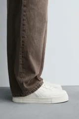 Zapatillas deportivas de estilo retro, color beige y marrón, con cordones y suela gruesa.