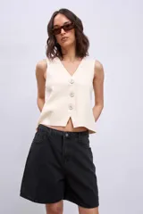 Chaleco de punto sin mangas, color rosado, con escote en V y cierre frontal de tres botones marrones.