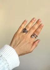 Anillo plateado de acero inoxidable con diseño de espiral dorado en el centro.